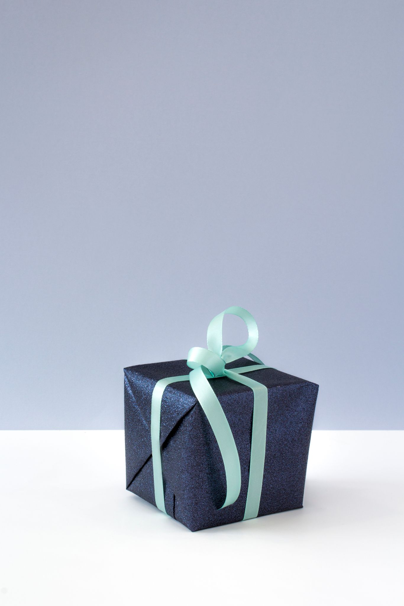 A sophisticated gift box wrapped in blue paper with a delicate ribbon, perfect for celebrations and surprises.